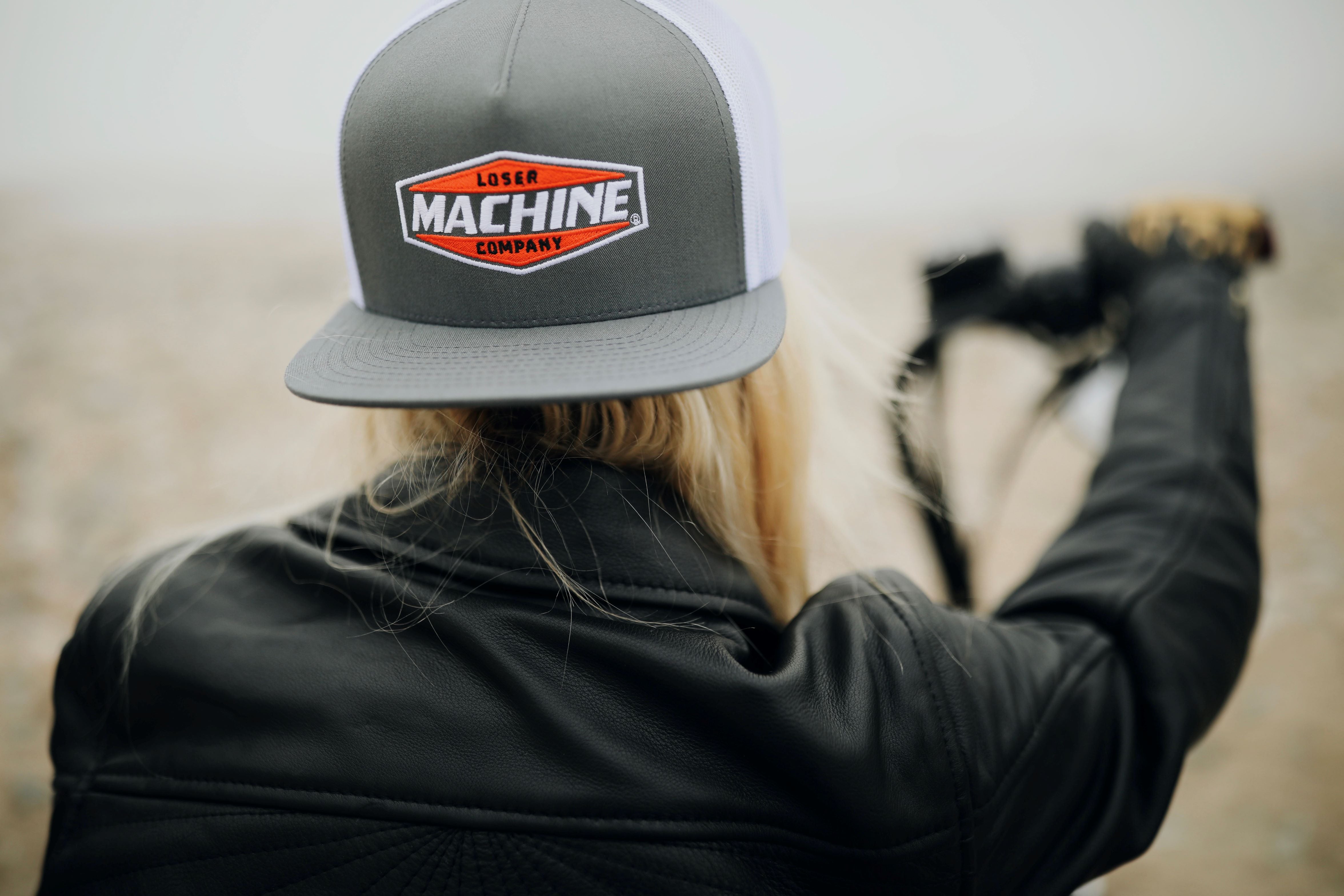 blonde girl on motorbike wearing grey loser machine snap back cap with black leather jacket 